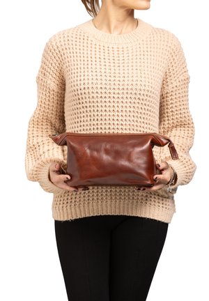 Pochette in pelle marrone con chiusura con zip, forma rettangolare, texture liscia e dettagli di cucitura sottili, appoggiata su uno sfondo di maglione a maglia leggera.