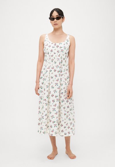 Gėlėta maxi suknelė balta spalva, su aptemptu liemeniu su plonomis petnešėlėmis ir laisvai krentančia sijono dalimi. Detalės - spalvoti maži gėlių raštai.
