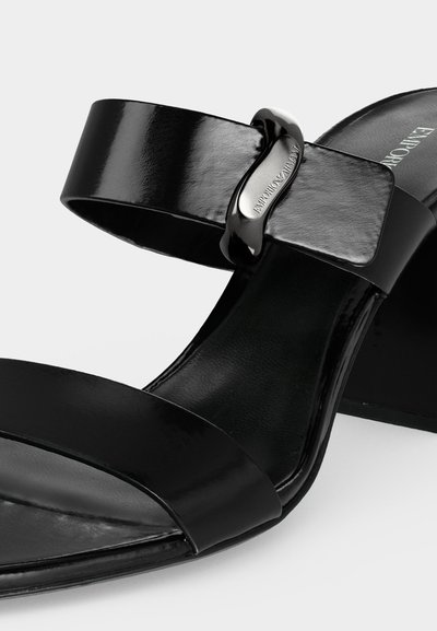 Μαύρο σανδάλι από δερμάτινο γκλος με ανοιχτό δάκτυλο, δύο λουριά, χαμηλό χοντρό τακούνι και μεταλλική αγκράφα με χαραγμένο το "EMPORIO ARMANI".