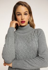 Maglione grigio a collo alto con un motivo di lavorazione a maglia testurizzato, polsini a costine e un design aderente. Tessuto morbido e profondità di colore sottile.