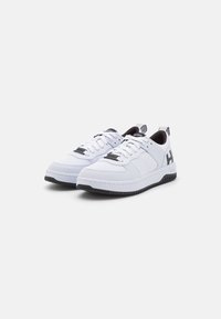 Sneaker bianco con tomaia sintetica liscia, dettagli in rete, suola in gomma nera e etichetta con logo sulla linguetta e sul tallone.