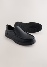 Chaussures à enfiler en similicuir noir avec un bout arrondi, des coutures décoratives et une semelle en caoutchouc texturée. Convient pour un usage décontracté.