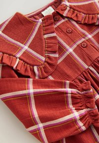 Rode geruite jurk met een gerimpelde kraag, knoopsluiting aan de voorkant en gathered mouwen. Gemaakt van textuurstof met witte, roze en groene accenten.