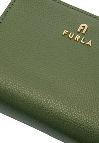 Zielony portfel z teksturowanej skóry z złotym logo "Furla", charakteryzujący się gładkimi krawędziami i kompaktowym designem.