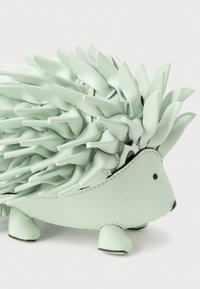 Figura de ouriço em couro verde menta com espinhos texturizados e detalhes pretos nos olhos e nariz. Apresenta corpo arredondado e pés pequenos.