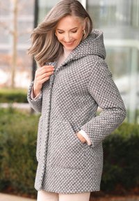 Manteau à carreaux gris et rose avec une capuche, en tissu texturé, boutons à l'avant, poches latérales et manches longues. Détails de contraste de couleur subtils.