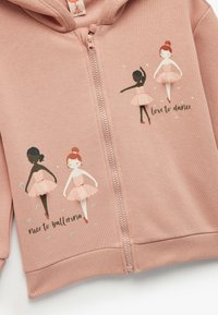 Sudadera con cremallera rosa que presenta dos ilustraciones de bailarinas en colores pastel, con el texto "me encanta bailar" y "encantada de ser bailarina" debajo.
