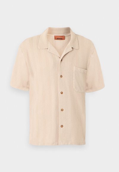 Chemise beige à manches courtes avec un motif chevrons texturé, une poche poitrine à l'avant et un col souple.