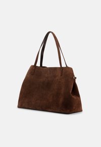 Gran bolso tote de ante marrón con dos asas largas y un pequeño detalle de hebilla lateral, mostrado sobre un fondo blanco liso.