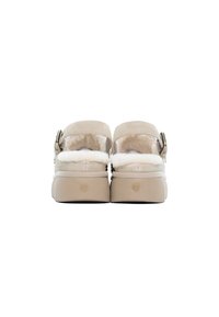 Scarpe slip-on beige con un morbido rivestimento in finta pelliccia, suola ammortizzata e un accento in metallo sulla fibbia. Taglia 37 indicata sul tacco.