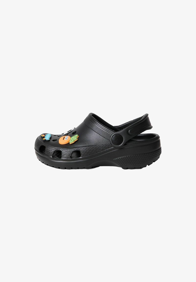 Sabot noir avec embout perforé, bride de talon et breloques colorées en forme de fruits et de personnages attachées sur le dessus.