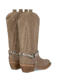 Botas vaqueras de ante marrón con costuras decorativas, correas trenzadas con rhinestones, anillos plateados y tacones de madera apilados, vistas desde un ángulo trasero.