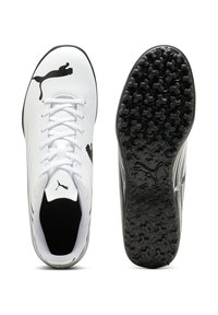 Scarpe da calcio bianche con dettagli neri, caratterizzate da una tomaia liscia, lacci e una suola in gomma nera testurizzata con tacchetti multidirezionali.