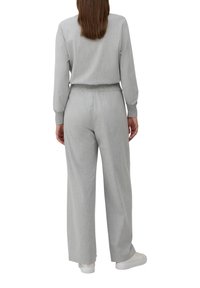 Ensemble de loungewear gris clair comprenant un pantalon ample et une taille ajustée. Le haut a des manches longues avec des poignets côtelés.