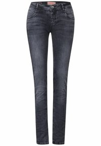 Jeans de mezclilla negra ajustados con un acabado desgastado, diseño de cinco bolsillos, cierre de botón y detalles de costura sutiles a lo largo de las costuras.