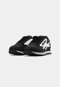 Sneaker sportive nere con accenti bianchi, realizzate con una parte superiore in suede e mesh, punta rotonda, design con lacci e suola esterna in gomma texture.