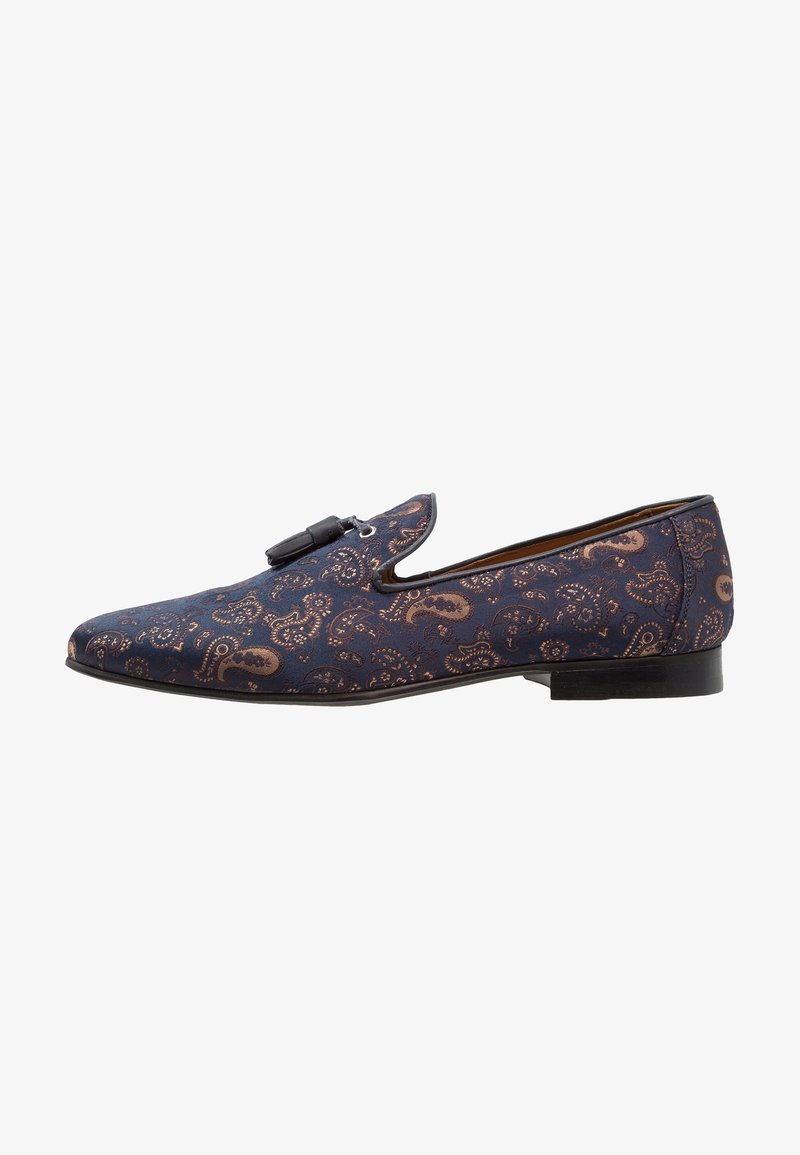 Chaussure en tissu bleu marine avec un motif cachemire bronze, dotée d'une semelle plate et d'un détail boucle décorative sur le dessus.