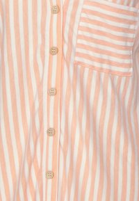 Randig skjorta med knappar i växelvis persika- och vita horisontella ränder, med en bröstficka och ljusa knappar.