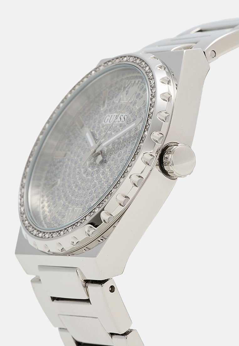 Orologio in acciaio inossidabile argento con quadrante testurizzato, decorazioni in cristallo e design della cassa angolato. Presenta un bracciale lucido e una corona.