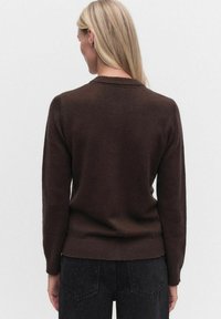 Brun stickad tröja med långa ärmar och ribbad krage, med en slät textur och en något avslappnad passform vid midjan.