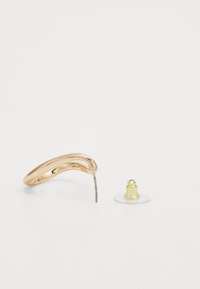 Boucle d'oreille en métal doré en forme de demi-lune avec une fine tige en métal. Accompagnée d'un dos en caoutchouc transparent avec une touche dorée. Surface lisse et brillante.