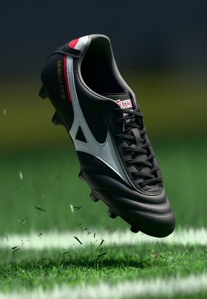Black leather soccer cleat with white accents, featuring a textured surface, laces at the front, and studs on the sole. "Morelia Club" label visible.