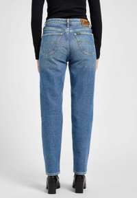 Blauwe denim jeans met een hoge taille, rechte pijpdesign en een kenmerkend bruine leren Lee-label op de achterkant van de tailleband.