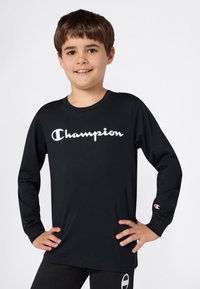 Camisa de manga larga negra hecha de algodón con el logo de "Champion" en blanco. Con un pequeño logo en la manga derecha.