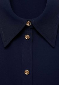 Navy blouse with a classic collar, featuring gold round buttons, smooth texture, and precise stitching along the edges.