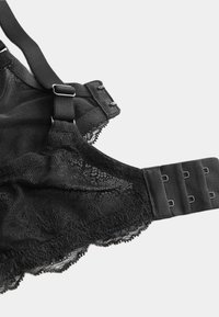 Sujetador de encaje negro con tirantes ajustables, cierre de gancho y ojal, material de malla ligero y borde de encaje con ondas en los extremos.