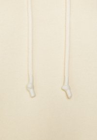 Krämfärgad sweatshirttyg med mjuk struktur; har vita flätade dragsko med rundade plastspetsar.