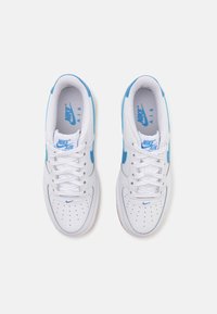 White sneakers with blue accents, featuring a smooth leather upper, perforated toe box, and flat white laces. Nike logo on tongue and side.