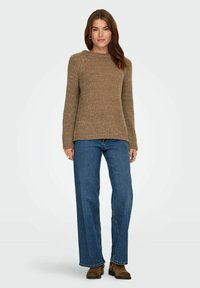 Suéter de punto color bronce con cuello redondo y mangas largas, combinado con unos jeans de pierna ancha azul y botas de tobillo marrones. Textura suave, diseño casual.