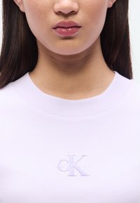 Λιλά πλεκτό πουλόβερ με ριμπ ύφανση, στρογγυλή λαιμόκοψη και κεντημένο λογότυπο "CK" σε τονική απόχρωση στο στήθος. Λ εία υφή με εφαρμοστή γραμμή.