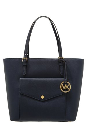 Granatowa skórzana torba na ramię z podwójnymi paskami, przednią kieszenią z złotym guzikiem oraz zawieszką z logo MK w kolorze złotym.