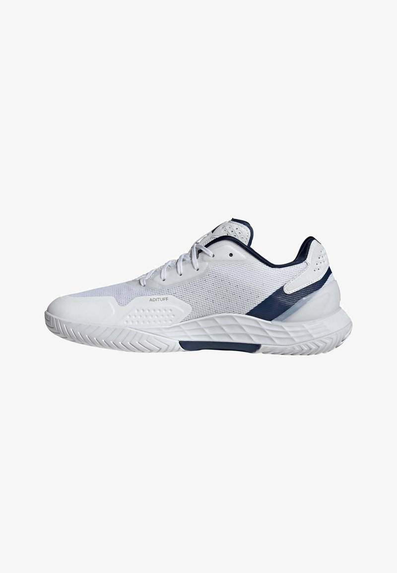 Chaussure de sport basse blanche et marine avec semelle texturée, tige en mesh, fermeture à lacets et étiquette « ADITUFF » sur le côté.