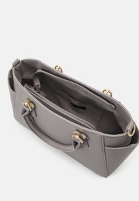 Sac à main gris avec une surface texturée, double poignée supérieure, accents en métal doré et un compartiment zippé à l'intérieur. Design structuré.