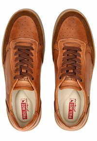 Sneaker in pelle marrone con dettagli perforati, lacci marroni e suola in gomma a contrasto. L'interno presenta una soletta con logo.