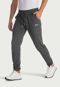 Gray sweatpants with an elastic waistband, drawstring, and side pockets. Features a small white "Bench." logo on the upper thigh.