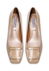 Scarpe in pelle verniciata beige con punta rotonda, scatola della punta quadrata e una grande fibbia decorativa sul davanti. Texture liscia e lucida.