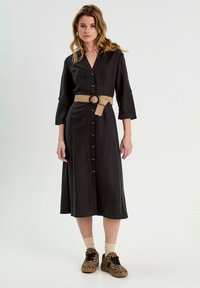 Robe noire à boutons, en tissu léger, dotée d'une taille ceinturée avec une ceinture naturelle tissée, des manches trois-quarts et d'une longueur midi.