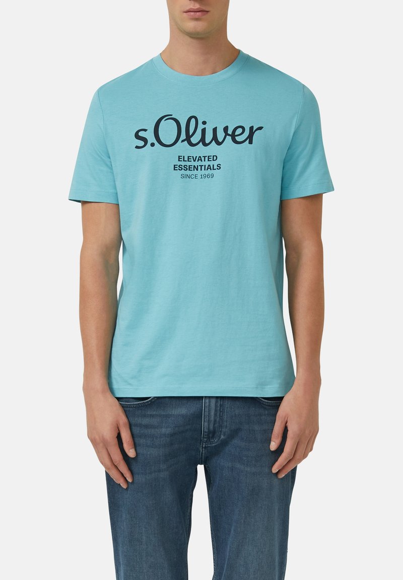 T-shirt en coton bleu clair à manches courtes, avec un texte noir "s. Oliver ELEVATED ESSENTIALS SINCE 1969" imprimé sur le devant.