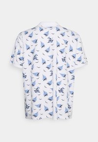 Bílé triko s krátkým rukávem, které má opakující se vzor modré plachetnice a racka. Tkanina se zdá být lehká s hladkým povrchem.