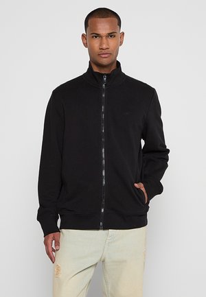 Sweat-shirt zippé noir en tissu doux, avec un col montant, des poches latérales et des poignets côtelés. Design simple, sans motifs ni logos.