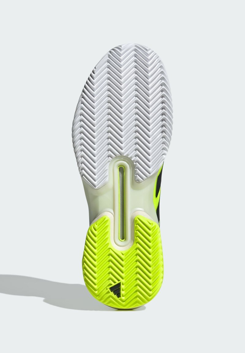 Semelle de chaussure avec un design en caoutchouc blanc et vert néon, présentant un motif en chevrons et un élément de coussin d'air visible au centre.