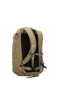 Mochila beige con panel trasero acolchado y correas ajustables. Presenta cremalleras y una hebilla en la parte delantera. Textura de tela suave.
