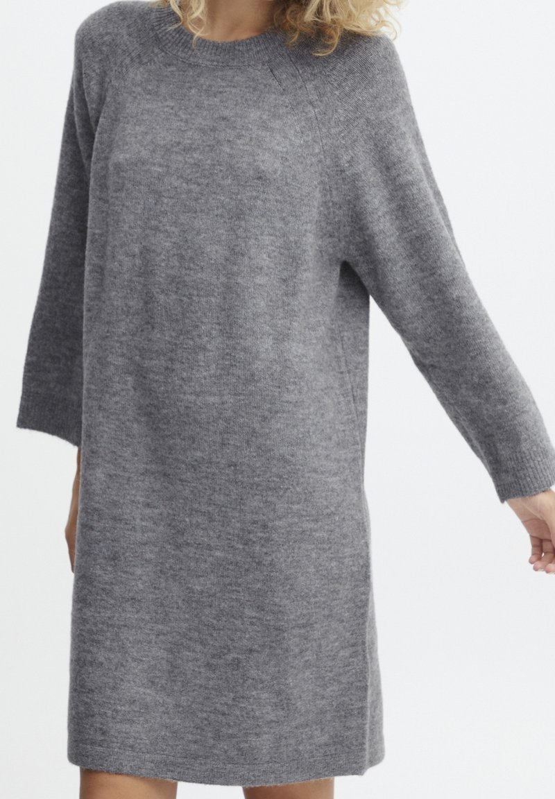 Robe grise en maille avec un col rond, des manches trois-quarts et une coupe décontractée, fabriquée dans un tissu doux et texturé, avec un ourlet juste au-dessus du genou.