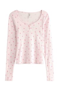 Lyserød langærmet bluse med rund hals, der har et delikat stribet mønster og små pink sløjfer. To-knaps lukning.