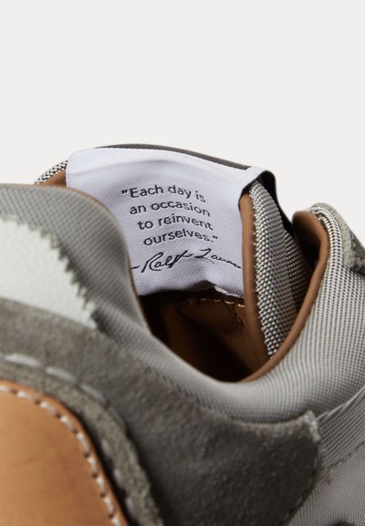 Langue intérieure de la chaussure avec une étiquette Ralph Lauren cousue affichant la citation : "Chaque jour est une occasion de se réinventer."