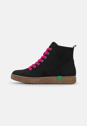 Czarny sneaker typu high-top z jaskrawo-różowymi sznurowadłami, brązową podeszwą i zieloną metką z logo marki na neutralnym szarym tle.